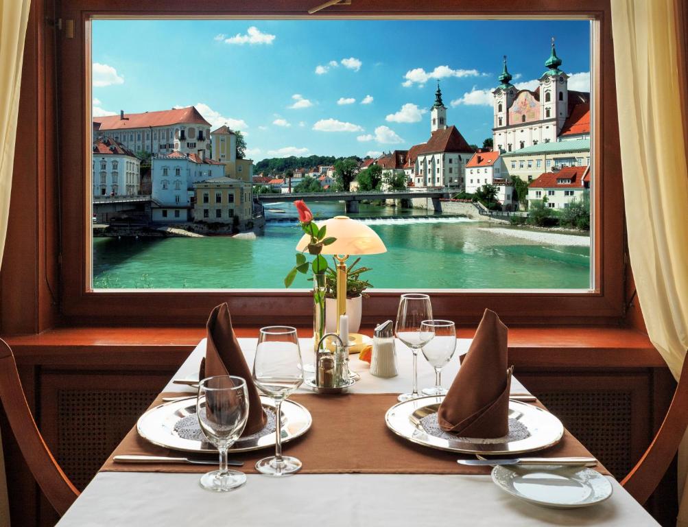 a table with a view of a river from a window at Hotel-Restaurant Minichmayr in Steyr
