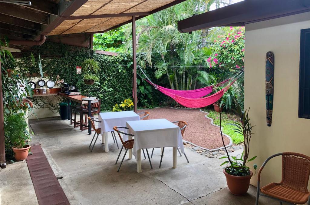 een patio met tafels en stoelen en een hangmat bij Hostel Dodero in Liberia