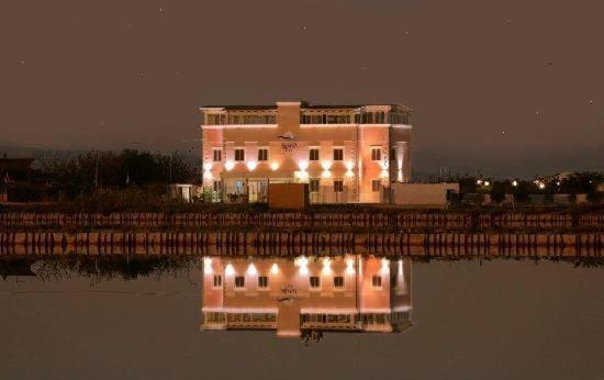 a building with lights reflecting in the water at night at Hotel Belvedere in Margherita di Savoia