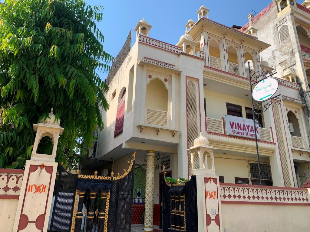 un gran edificio blanco con una puerta y un árbol en Vinayak Guest House, en Jaipur