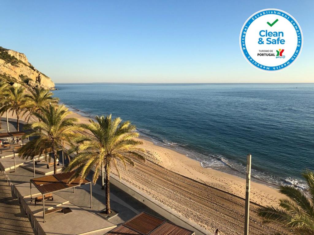 a view of a beach with palm trees and the ocean at APARTAMENTO MAR WITH PARKINg in Sesimbra