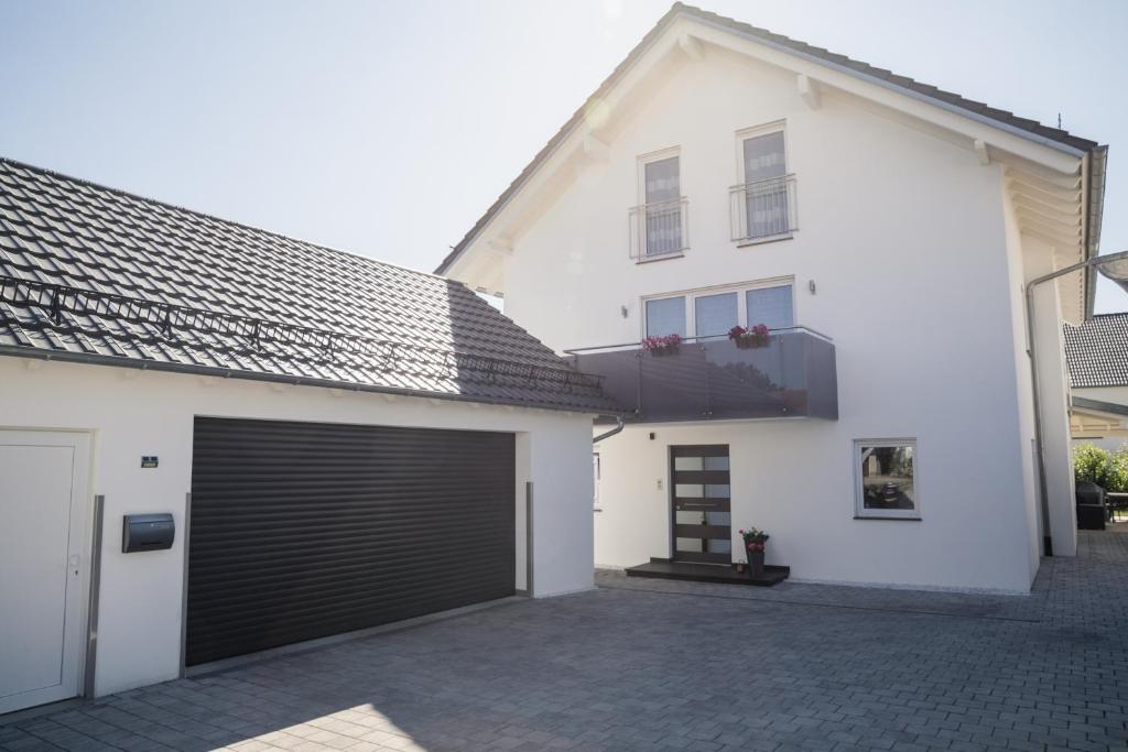 ein weißes Haus mit einer schwarzen Garagentür in der Unterkunft Ferienwohnung am Zeppelin Hangar in Friedrichshafen