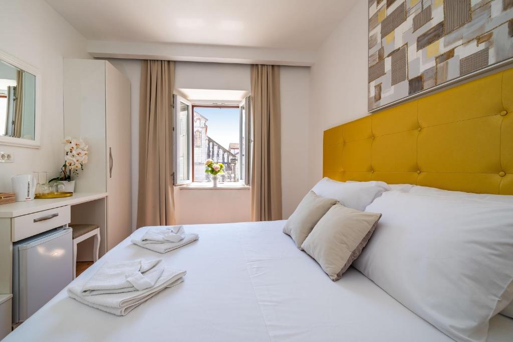 - une chambre avec un grand lit blanc et une tête de lit jaune dans l'établissement Luxury rooms Zadar old town, à Zadar