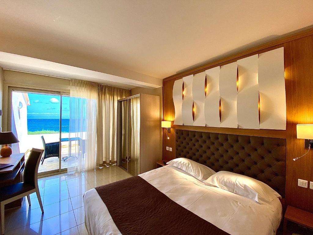 a bedroom with a bed and a desk and a window at Hotel Tettola in Saint-Florent