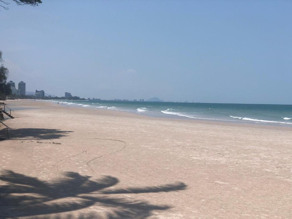 a beach with a shadow of a palm tree on it at Sea you pool villa Hua Hin in Hua Hin