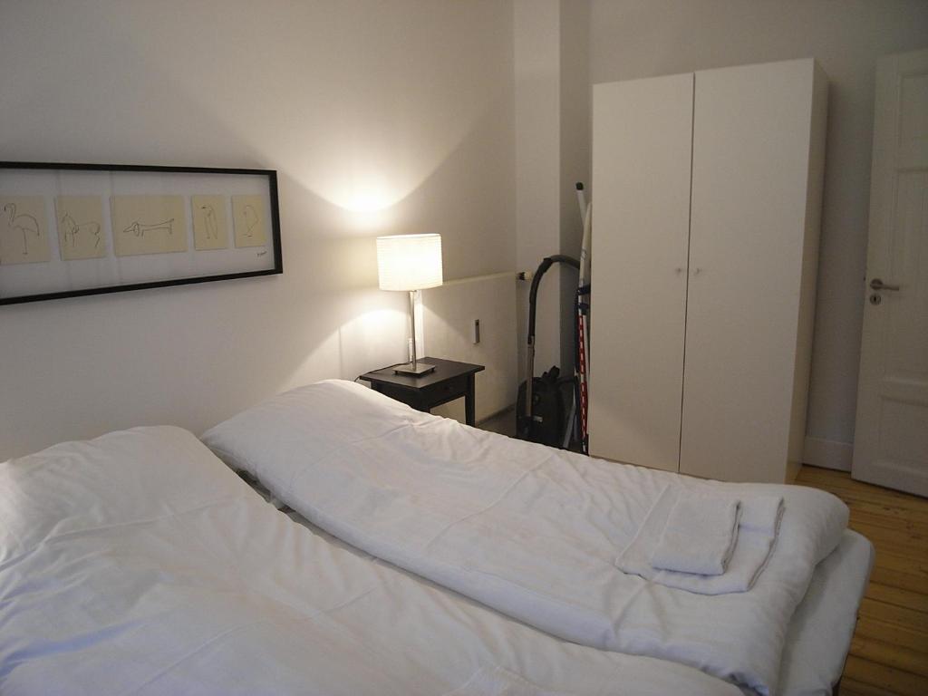 a bedroom with a bed with white sheets and a lamp at Ydunsgade in Copenhagen