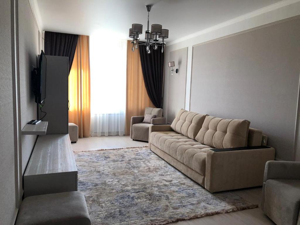 sala de estar con sofá y TV en 2-ухкомнатная современная новая квартира в центре города, en Kostanái