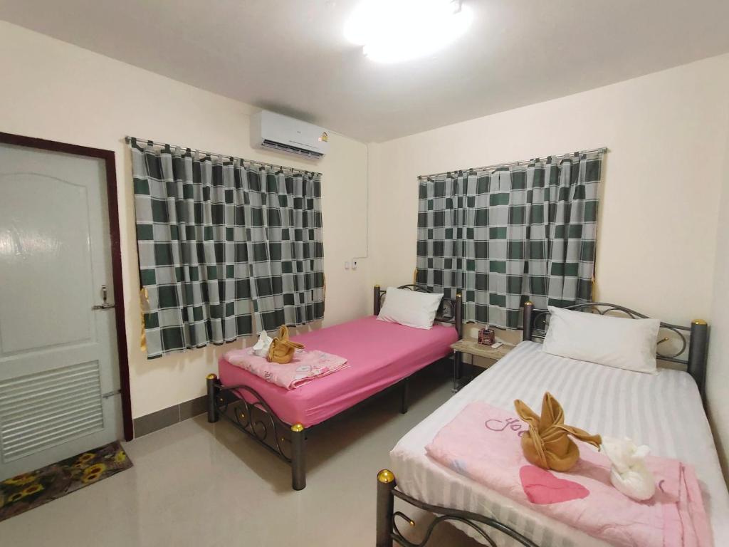 1 Schlafzimmer mit 2 Betten und einer rosa Decke in der Unterkunft ทองอุไร โฮมสเตย์ in Mae Sai