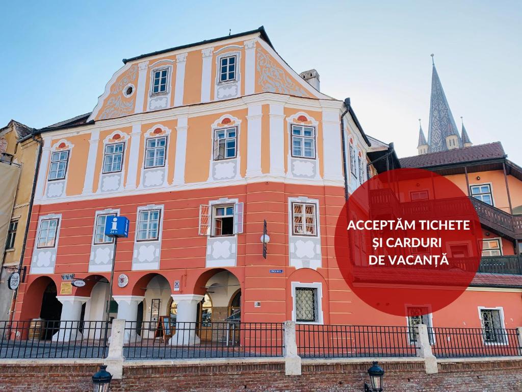 un gran edificio naranja con una señal roja delante de él en Hotel Casa Luxemburg- Newly Renovated en Sibiu