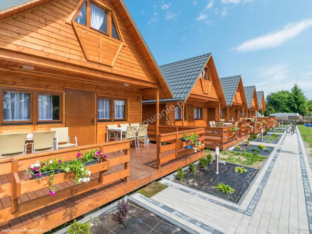 une rangée de maisons en bois avec bancs et tables dans l'établissement ATJ Bursztynowy Zakątek, à Kąty Rybackie