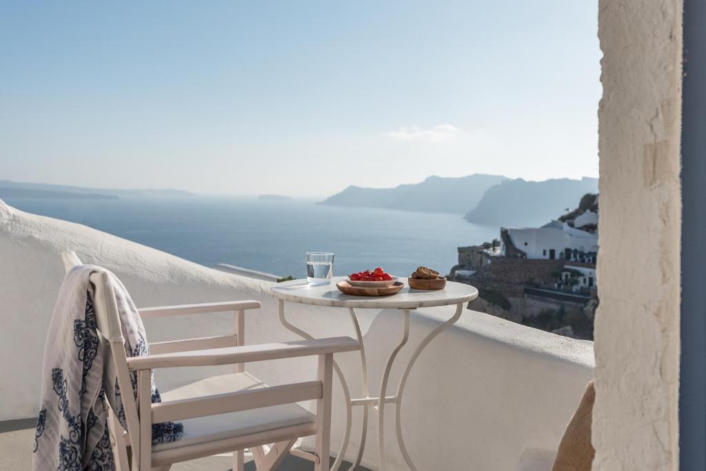 a table and chairs on a balcony with a view at White Cellar cave houses by Cycladica in Oia
