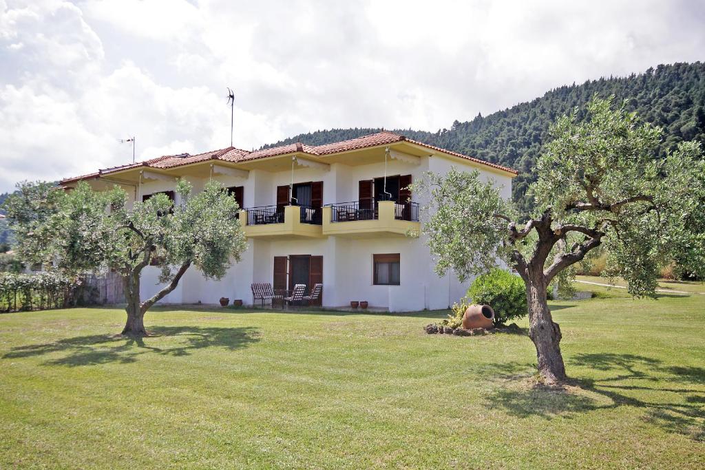 a white house with two trees in a yard at Studios Stella Vourvourou in Vourvourou