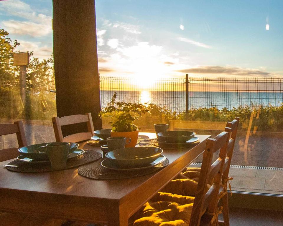 drewniany stół z miskami i talerzami przy zachodzie słońca w obiekcie Na Klifie Cafe Apartament w mieście Ustronie Morskie