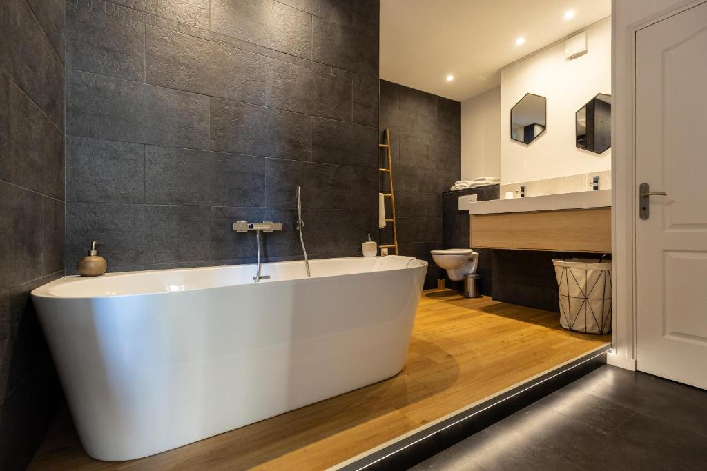 La salle de bains est pourvue d'une grande baignoire blanche. dans l'établissement La Suite - Honfleur, à Honfleur