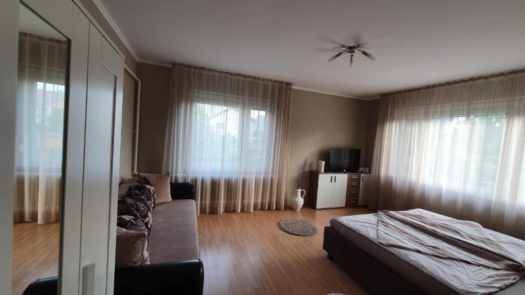 a bedroom with a bed and a couch and windows at Ilike Home in Balatonfüred