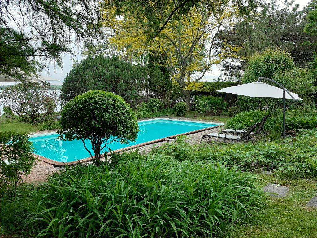 una piscina con sombrilla, mesa y sillas en Chambre bord de l'eau oka, en Oka