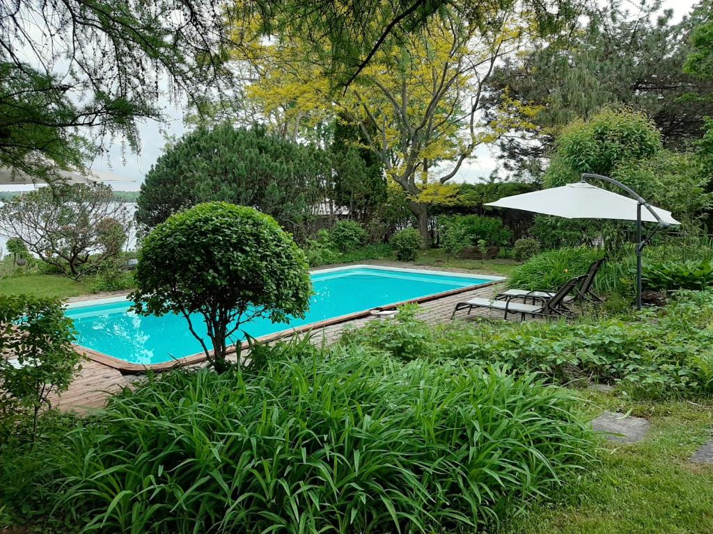 a swimming pool with an umbrella and a table and chairs at Gîte le 308 Chambre bord de l'eau oka in Oka