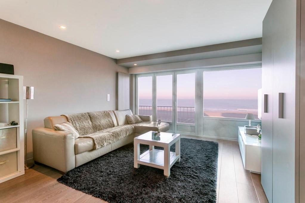 een woonkamer met een bank en een tafel bij Montezuma luxe studio met frontaal zeezicht zonder aparte slaapkamer in Oostende