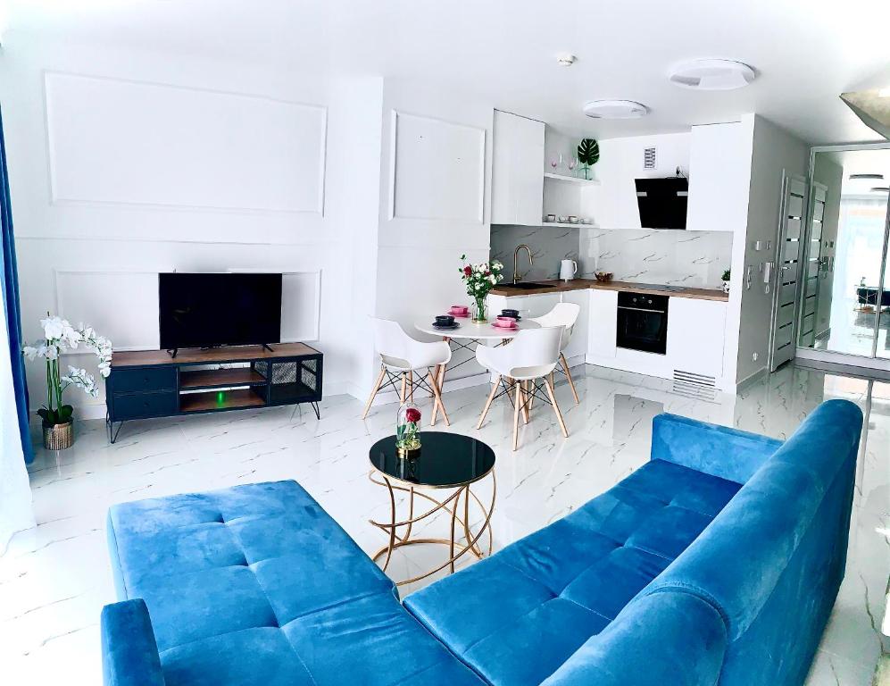 a living room with a blue couch and a kitchen at Apartament Bursztynek Jantar Park in Jantar