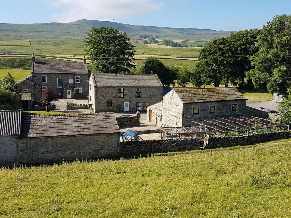 a group of houses on a hill with a field at Old Camms Holiday Cottages in Askrigg