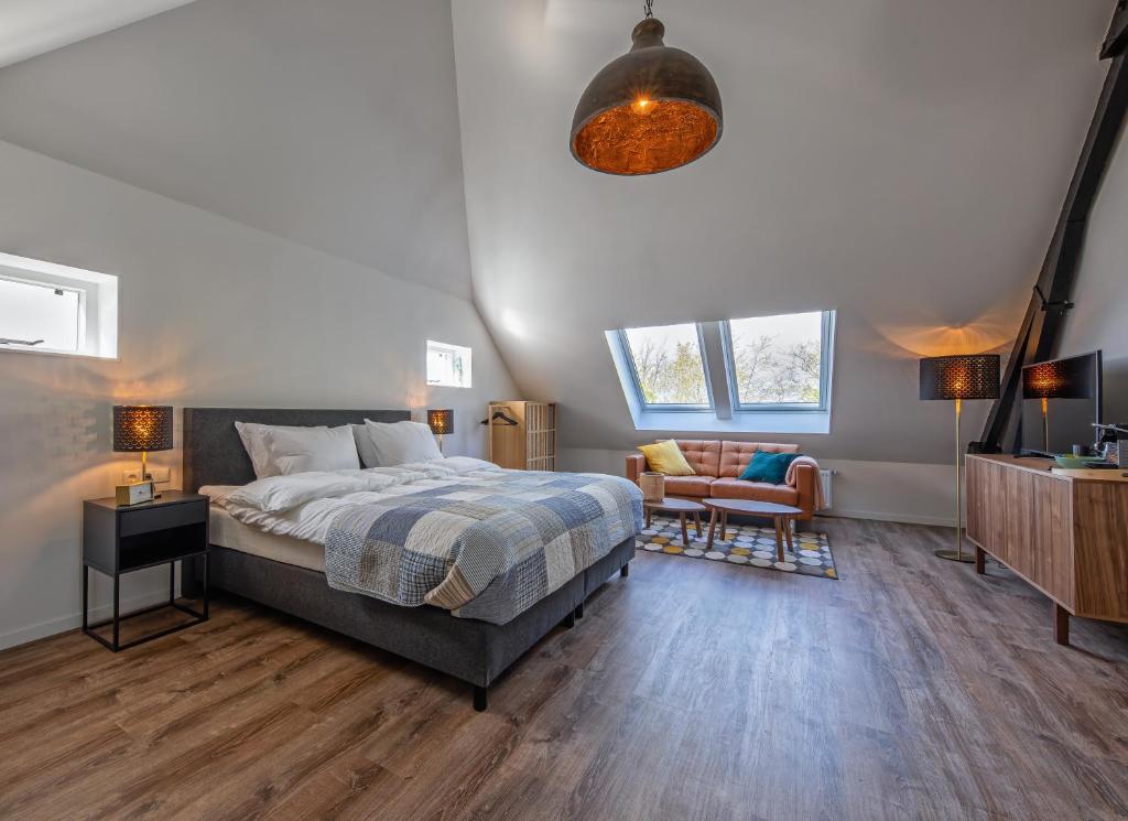 Noorderhaecks Suites & Apartment في 't Horntje: غرفة نوم بسرير واريكة وتلفزيون