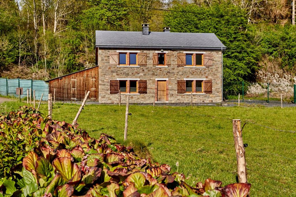 a stone house in the middle of a field at Le Rocher Du Lac in Houffalize