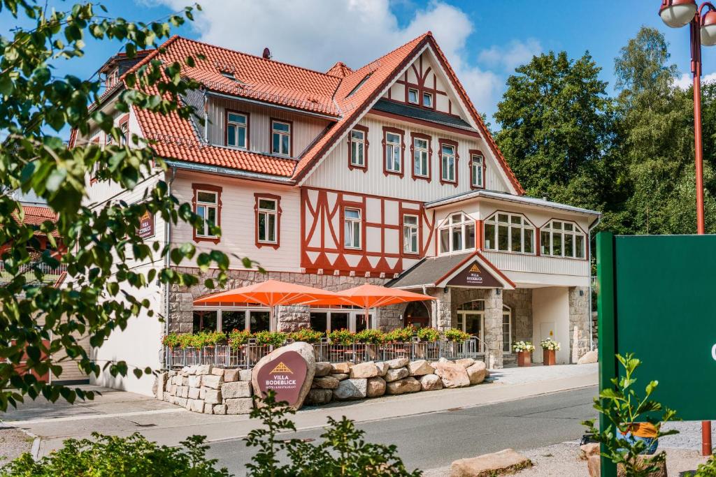 une grande maison avec des parasols orange devant elle dans l'établissement Hotel Villa Bodeblick, à Schierke