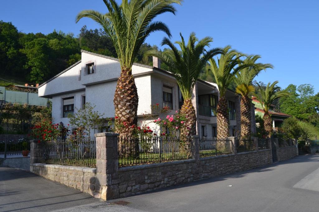 una casa con palmeras frente a una valla en Apartamentos Las Palmeras, en Cangas de Onís