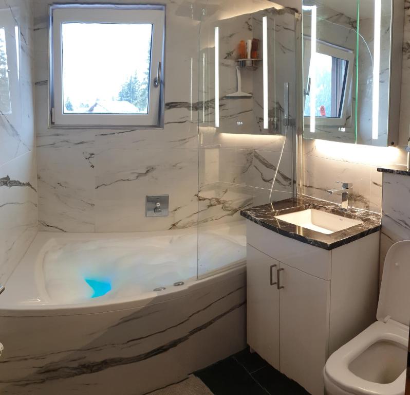 a bathroom with a tub and a sink and a toilet at Premium Jacuzzi Central Verbier Studio, High Floor in Verbier