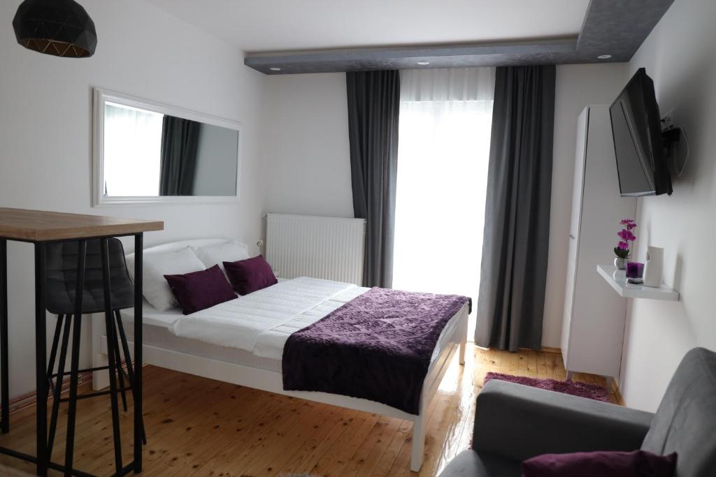 una camera da letto con un letto con lenzuola viola e una finestra di Apartman Ena a Nova Varoš