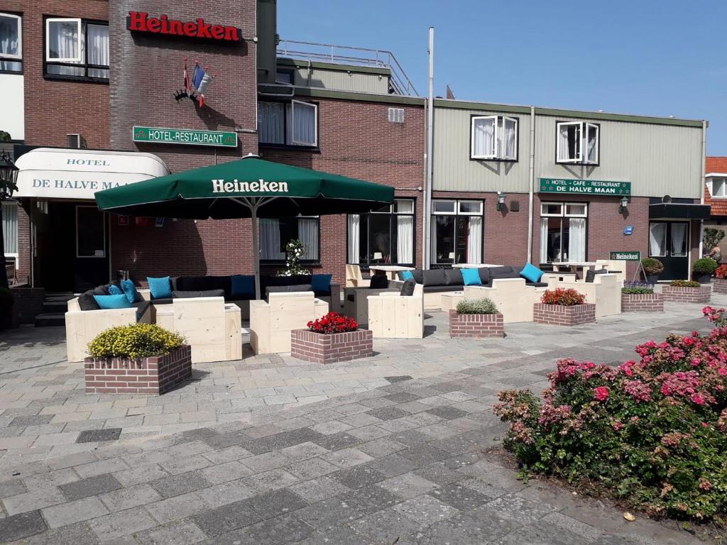 De Halve Maan في Bovenkarspel: فناء فيه طاولات وكراسي امام مبنى