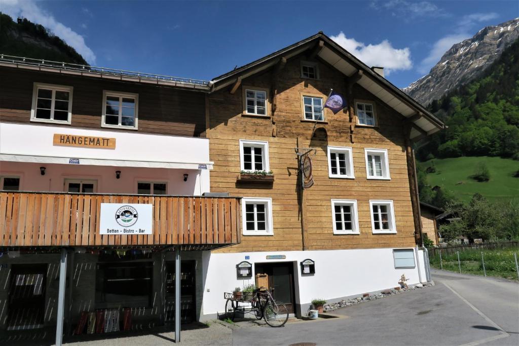 a large wooden building in front of a mountain at Aktivhostel HängeMatt in Matt