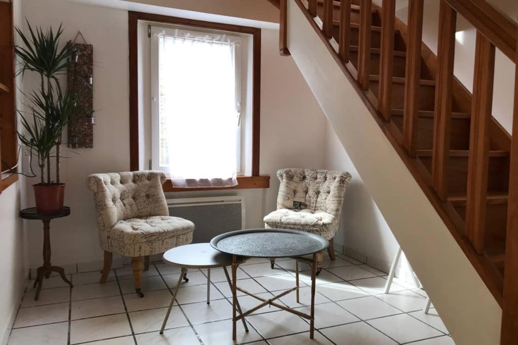 a room with two chairs and a table and stairs at Charmante maison de pêcheur in Barfleur