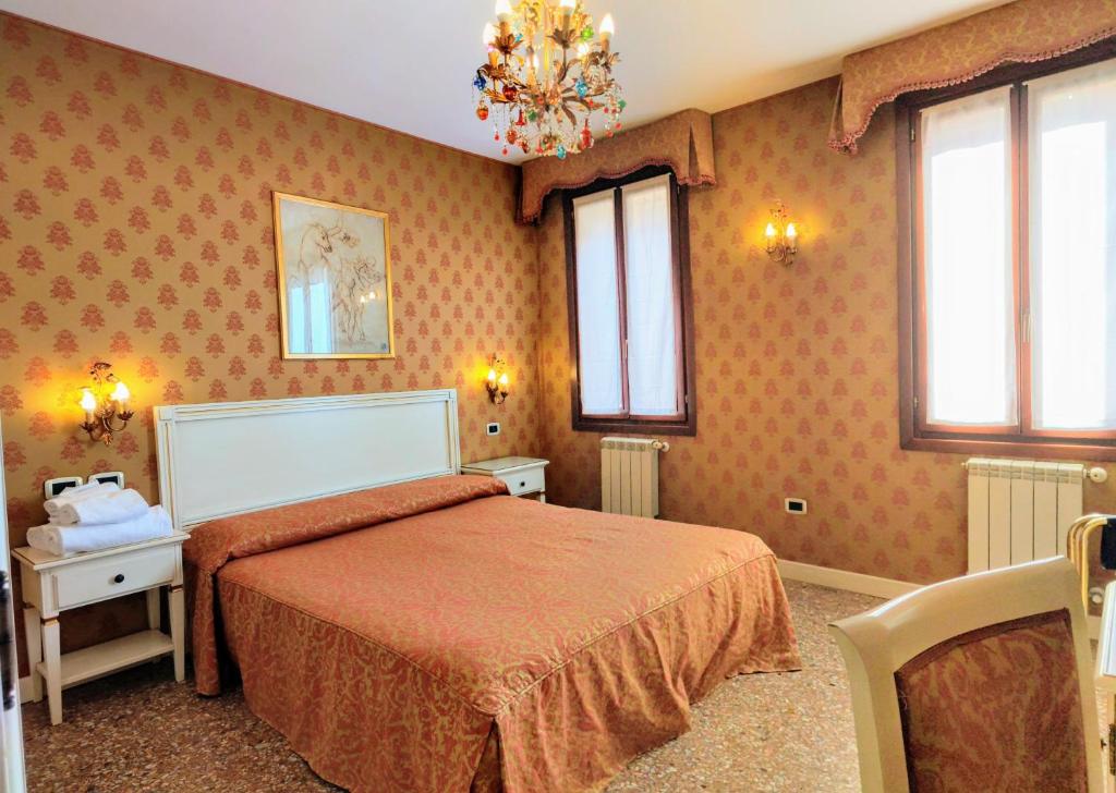 a bedroom with a bed with orange sheets and windows at Ca' San Vio in Venice