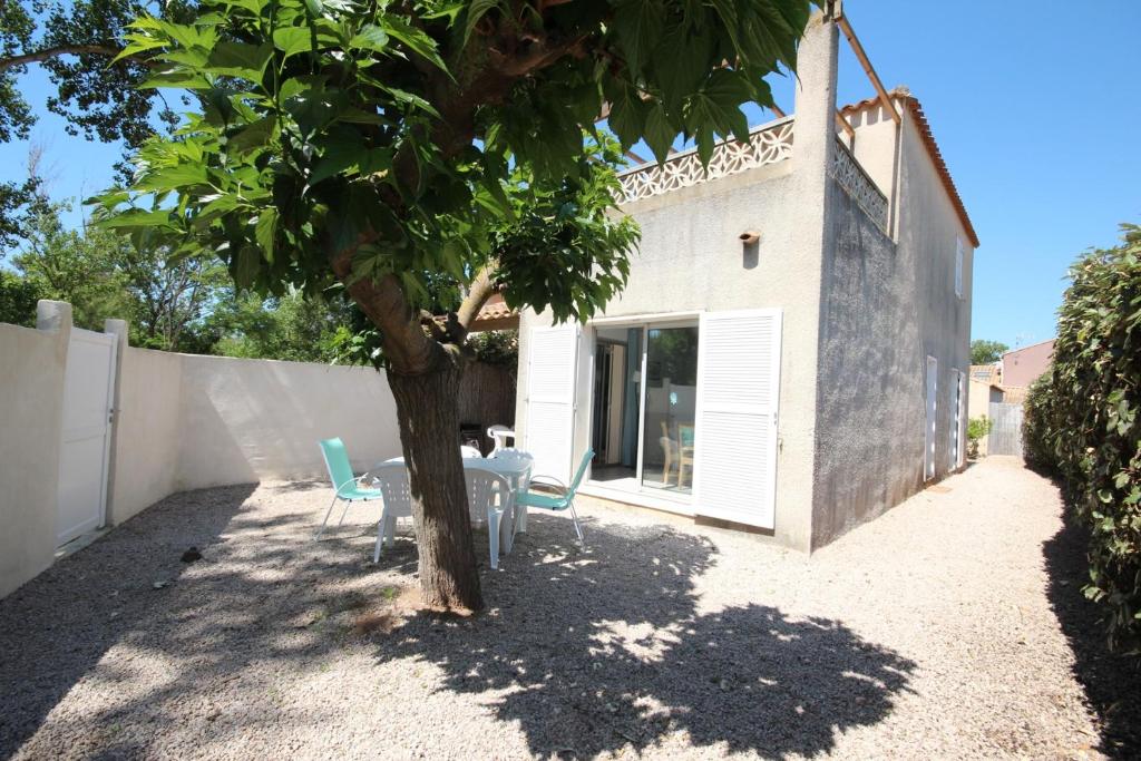 un patio avec une table et des chaises sous un arbre dans l'établissement A quelques pas de la plage Belle Maison de vacances, 6 à 8 couchages, 3 chambres, balcon, jardin, parking, 50 m de la mer- PORTIRAGNES PLAGE LXBOSQD, à Portiragnes