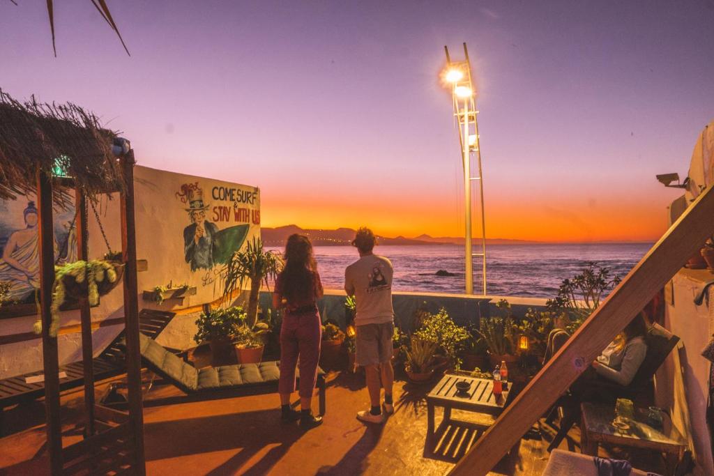 dos personas de pie en un balcón viendo la puesta de sol en Agüita House, en Las Palmas de Gran Canaria