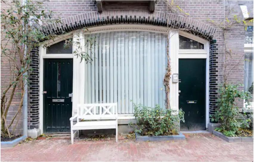 a white bench in front of a building with two doors at Marijke's guestroom in Amsterdam