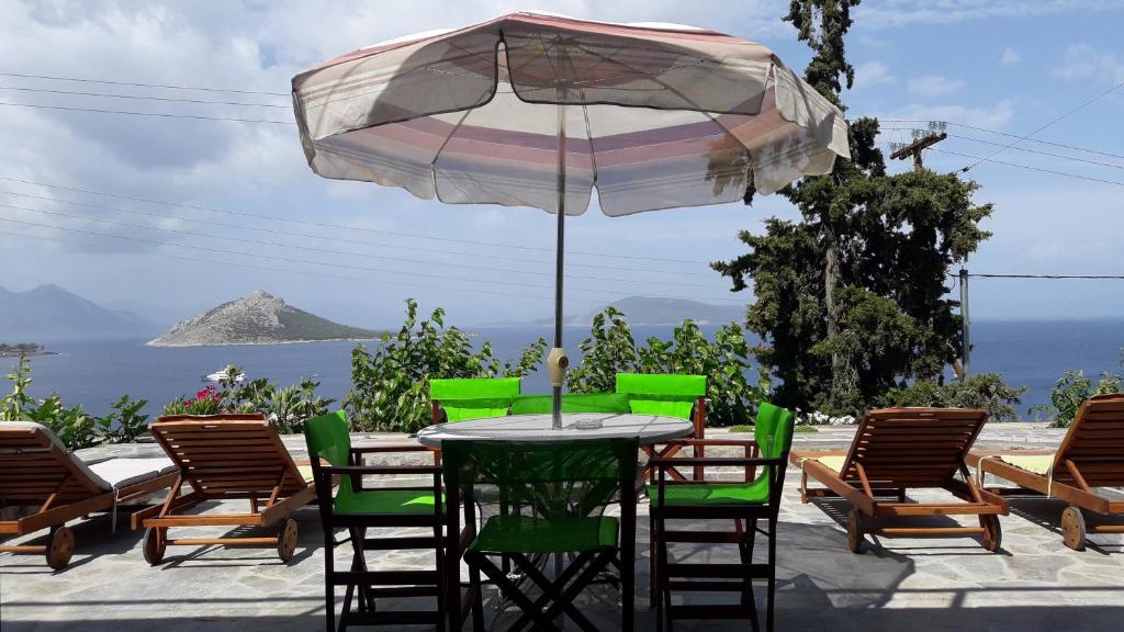 einen Tisch mit Stühlen und einem Sonnenschirm auf einer Terrasse in der Unterkunft Fantastic House with a Wonderful View of the Sea in Kapótidhes