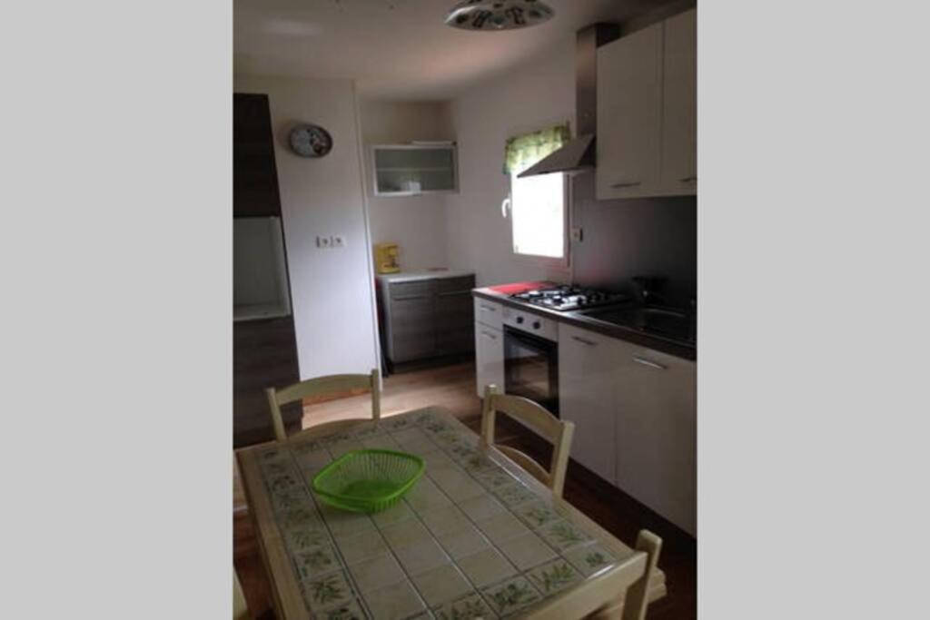 eine Küche mit einem Tisch, einem Tisch und Stühlen in der Unterkunft Maison adossée in LʼAiguillon-sur-Vie