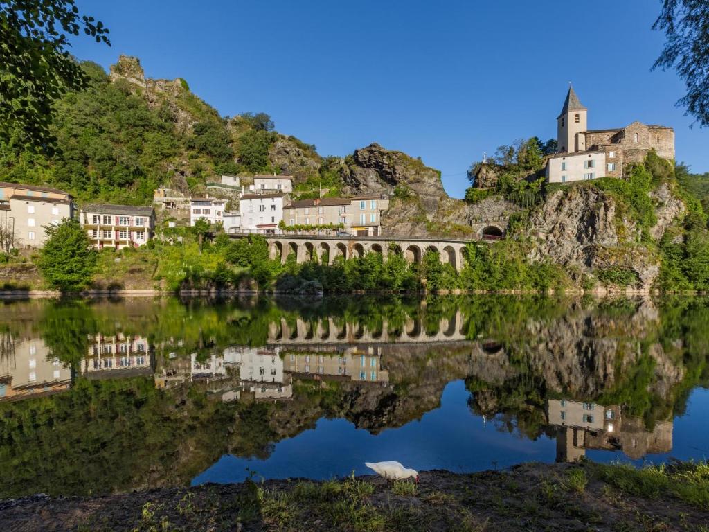 eine Brücke über einen See mit Häusern auf einem Berg in der Unterkunft Les Gîtes du Rocher et de la Boucle du Tarn in Ambialet