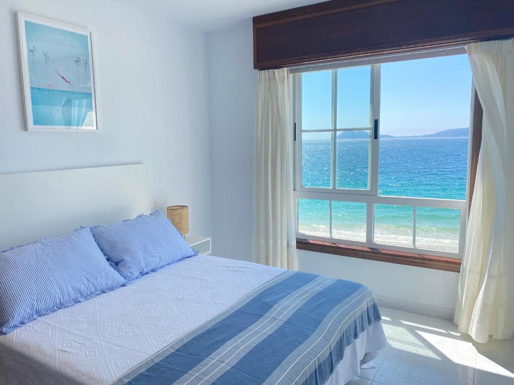 1 dormitorio con cama y ventana con vistas al océano en OH LA LIFE MAR, en Portosín