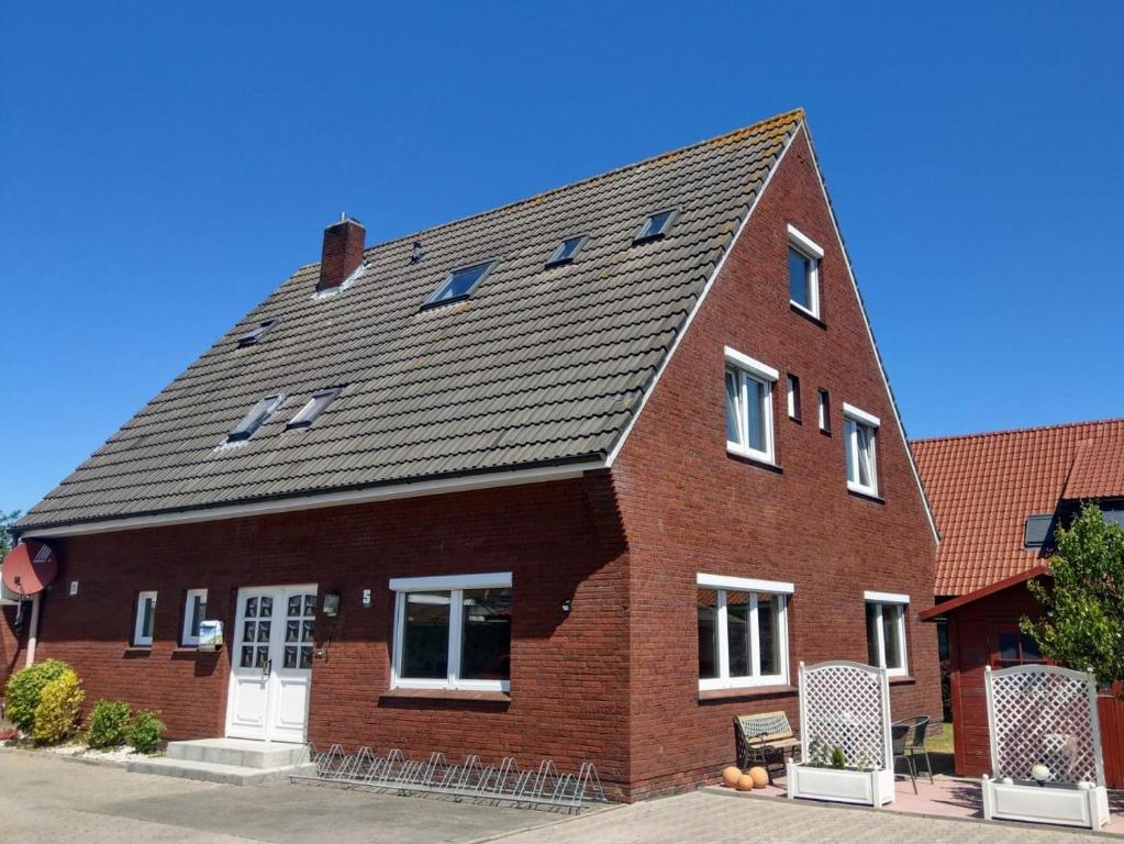 una casa di mattoni rossi con tetto nero di Pension An der Reling a Dornumersiel