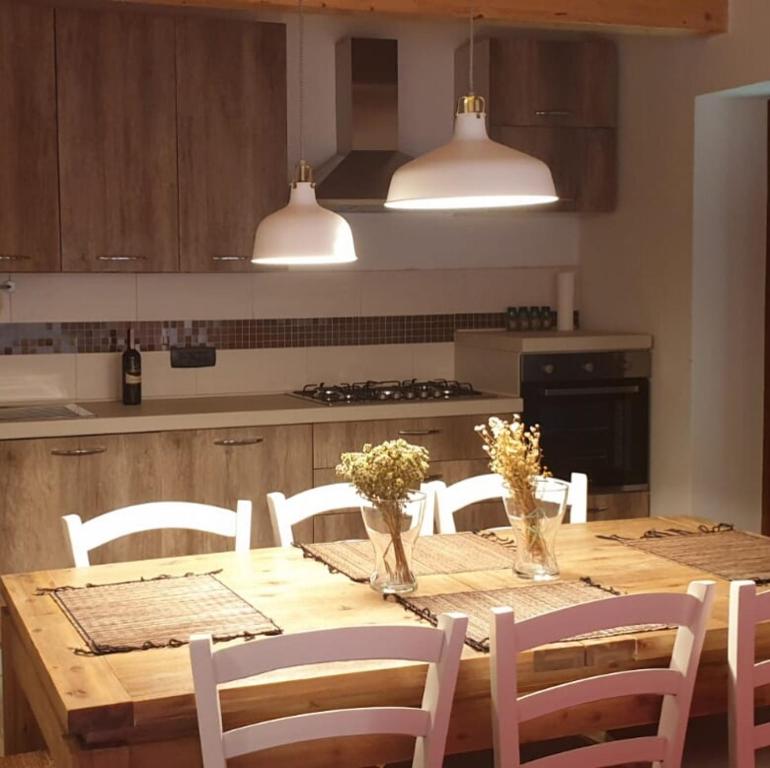La Locanda dei Cavalieri في مورمانو: مطبخ مع طاولة خشبية مع كراسي بيضاء