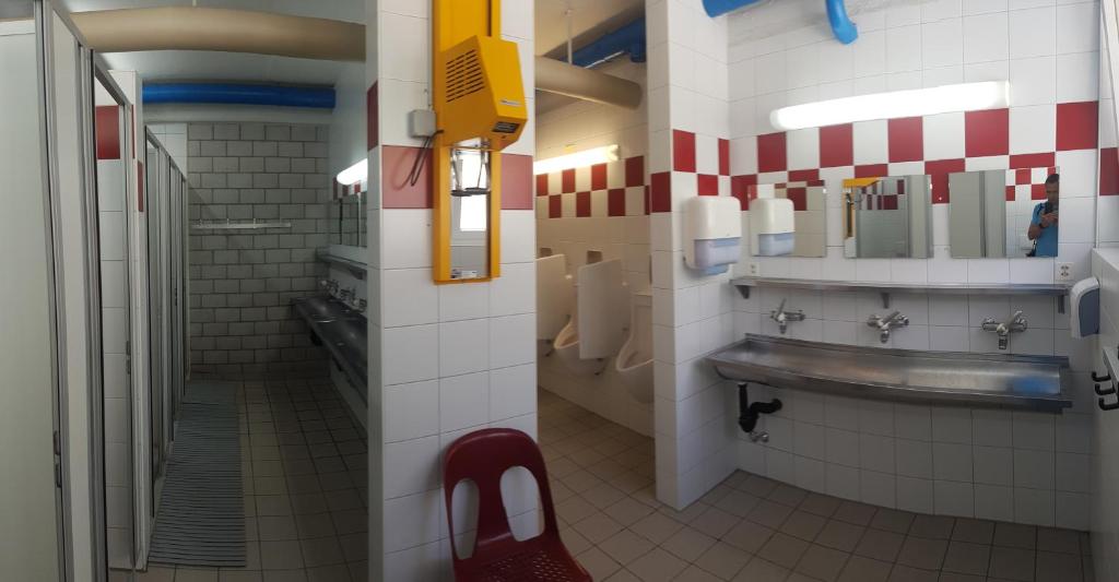 un bagno pubblico con lavandino e sedia rossa di Campingplatz mit Restaurant & Sportarena Leukerbad a Leukerbad