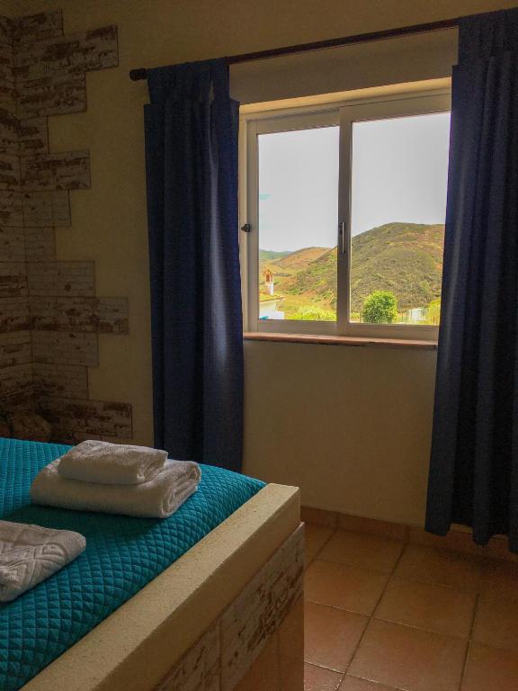 a bedroom with a window and a bed with towels on it at Carrapateira Lodge in Carrapateira