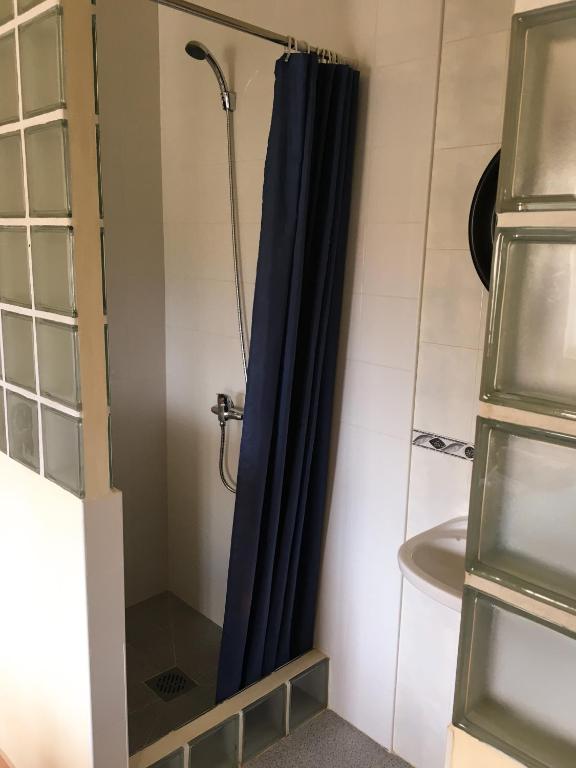 a bathroom with a shower with a blue shower curtain at Carrapateira Lodge in Carrapateira