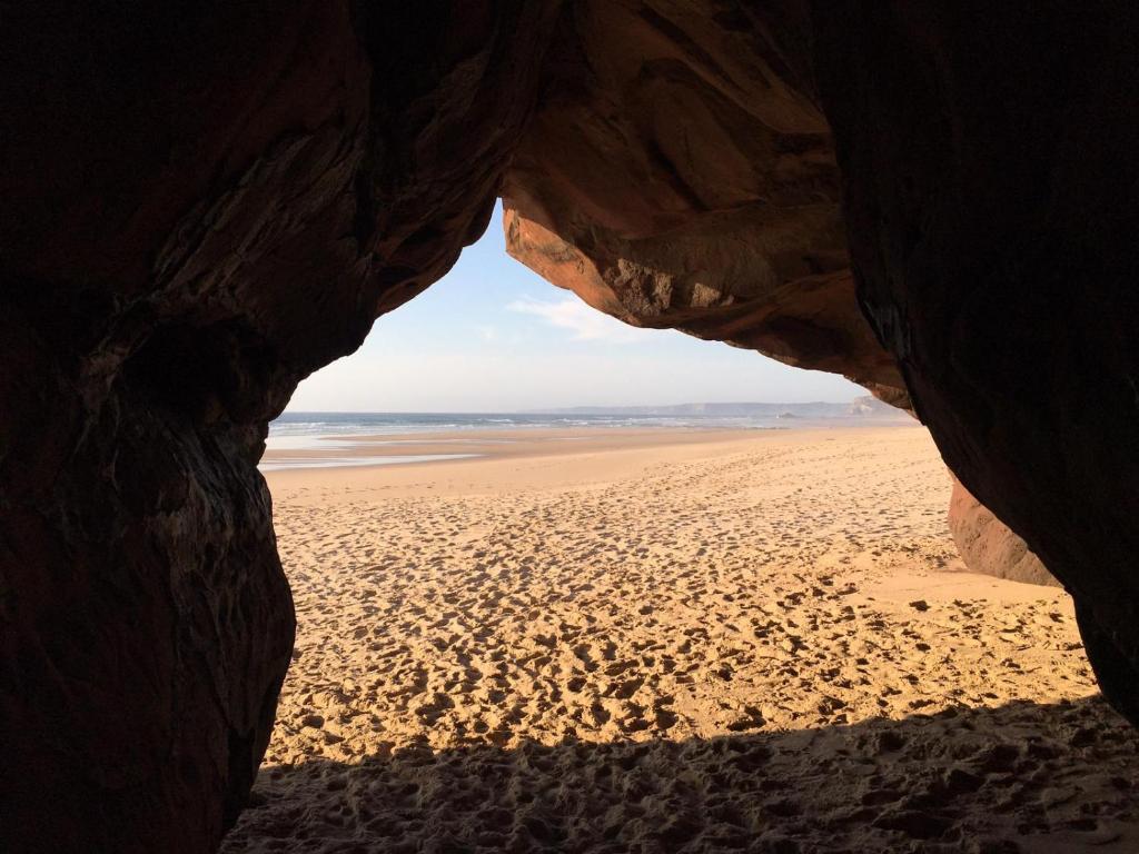 a view of a beach through a cave at Carrapateira Lodge in Carrapateira
