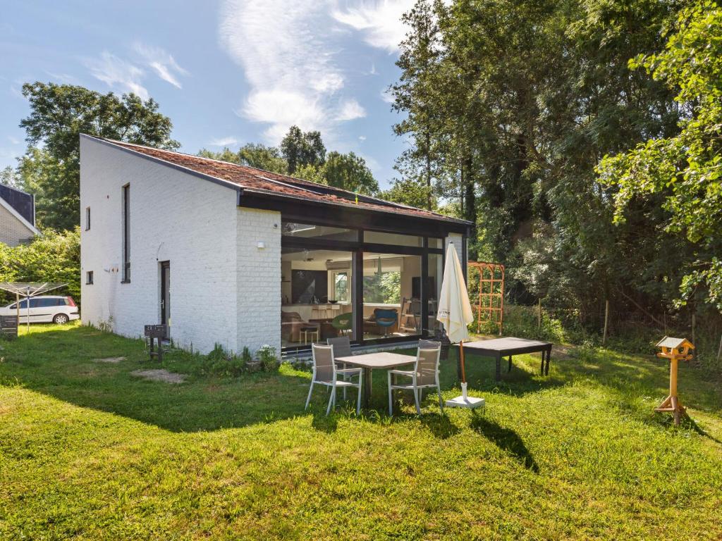 un pequeño edificio blanco con mesa y sillas en Sun kissed Villa in Kobbegem with Private Garden, 