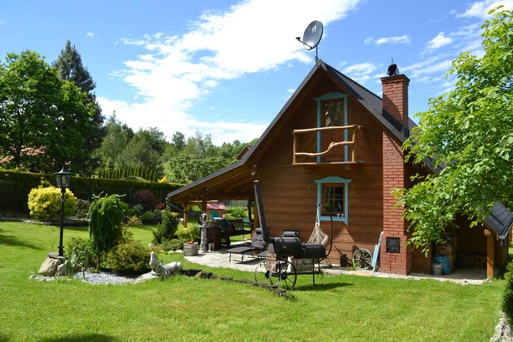 una pequeña casa de madera con un patio de césped en Domek pod Jaworami, en Sułkowice