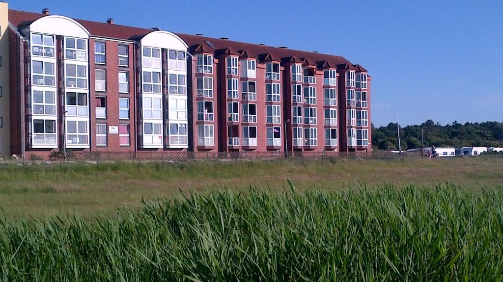a large red building in a field of grass at Haus Horizont Fewo Nr 21 in Cuxhaven